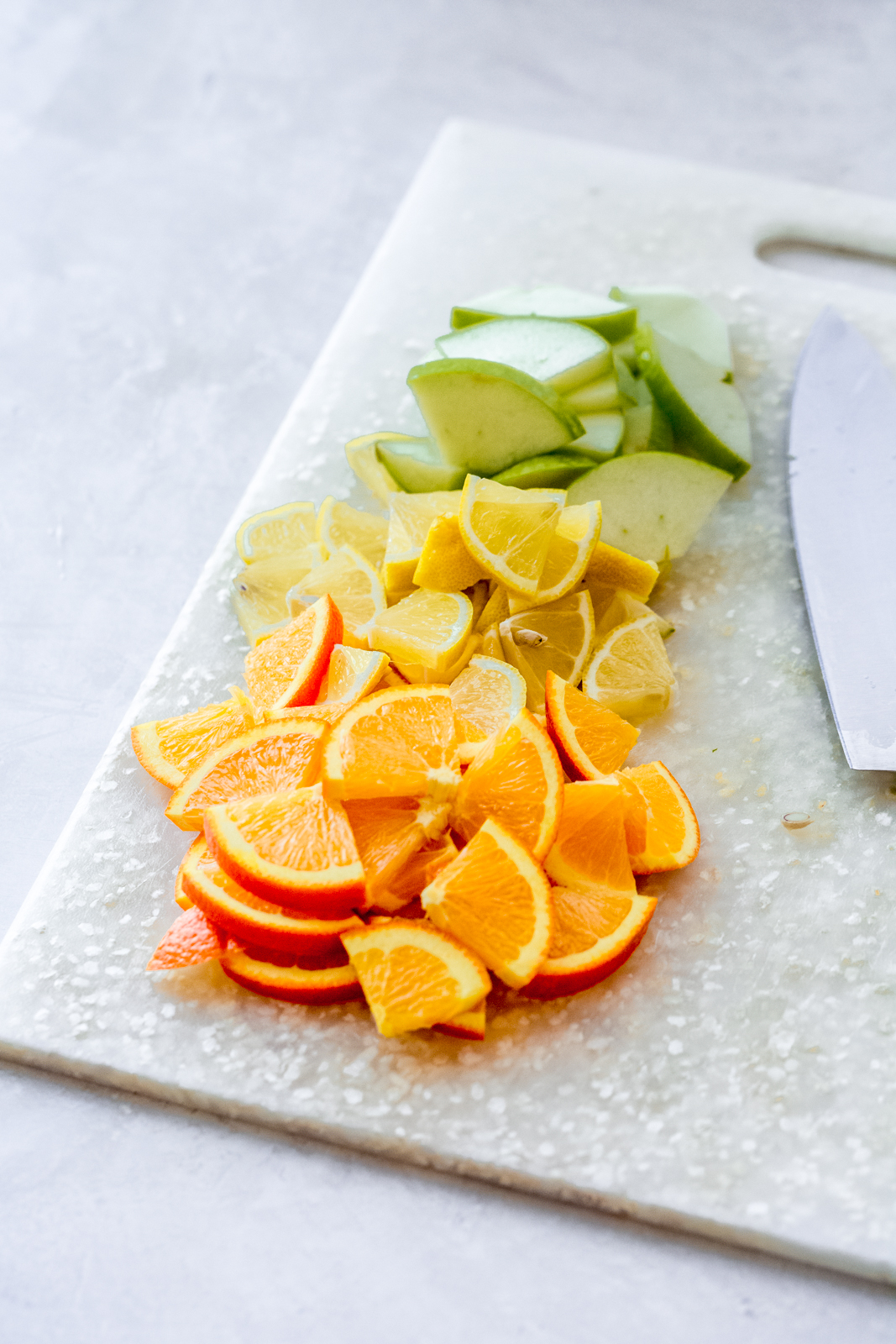 cut up citrus slices wedges on white cutting board with knife