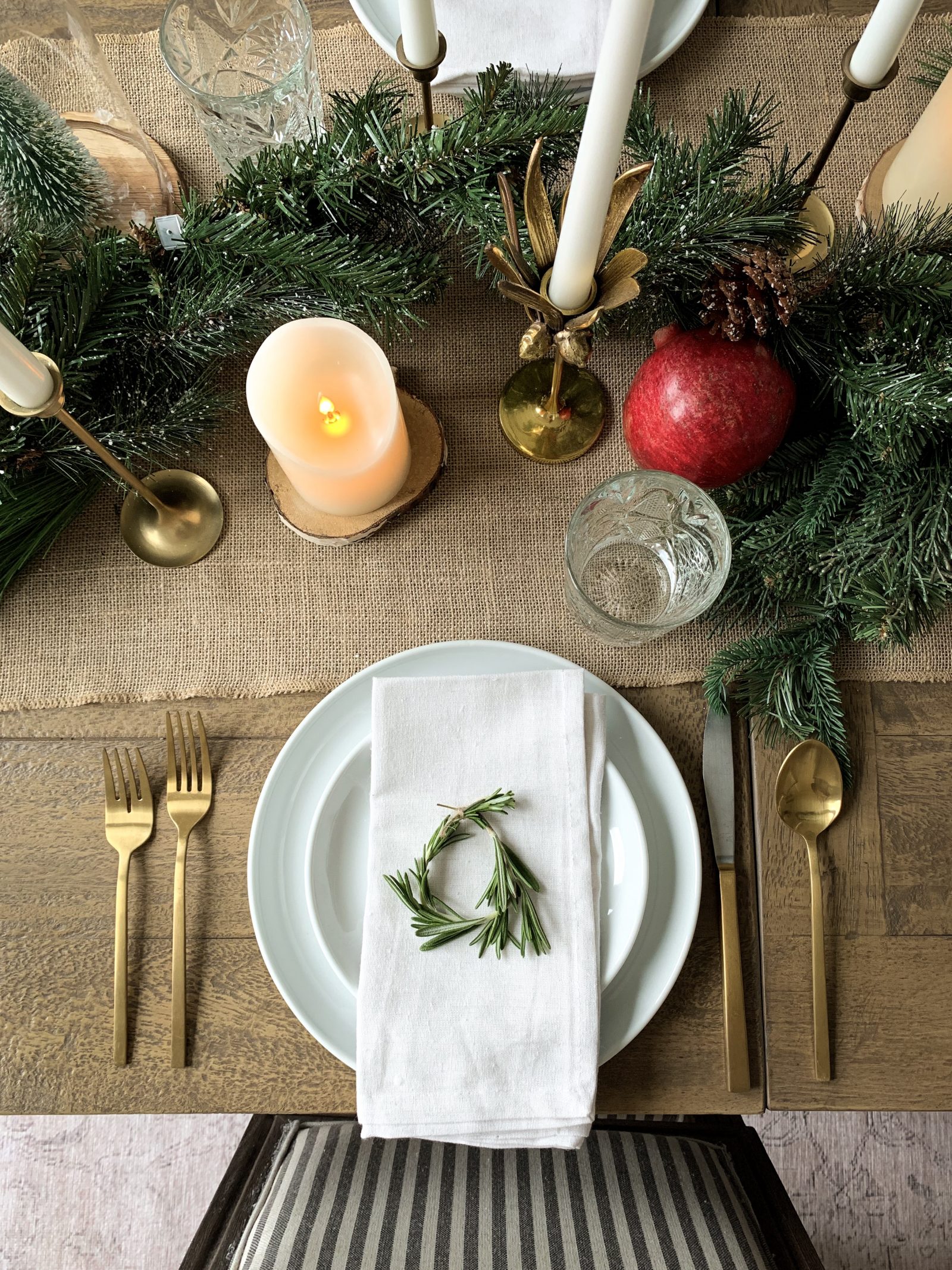 close up of place setting for a holiday tables cape with neutral tones with evergreens