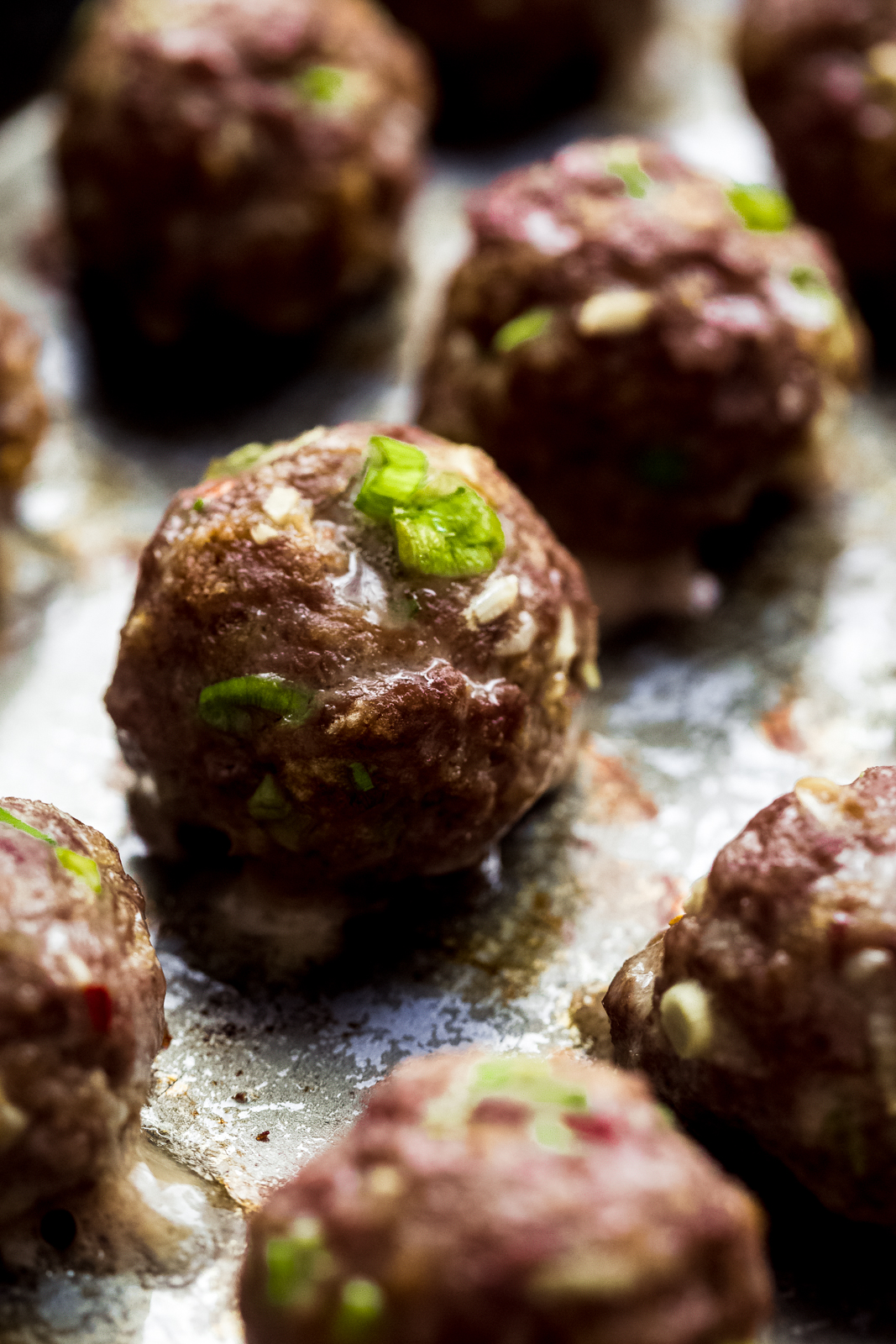 close up of baked beef meatballs with scallions showing