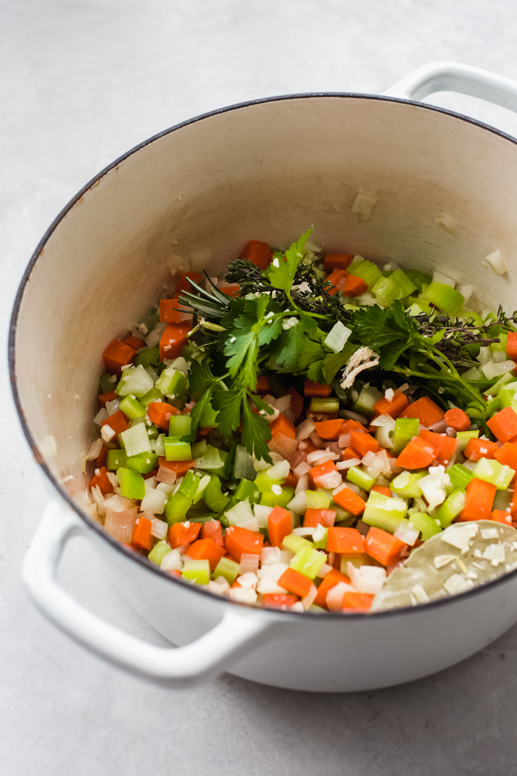 sautéed veggies with bouquet garni in white cast iron pot