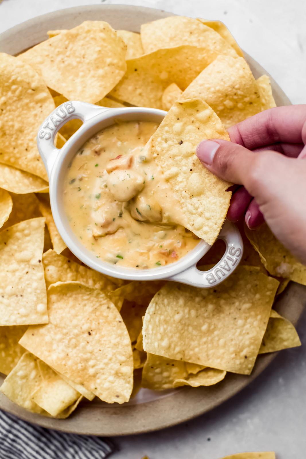 hand dipping dip in prepared Queso