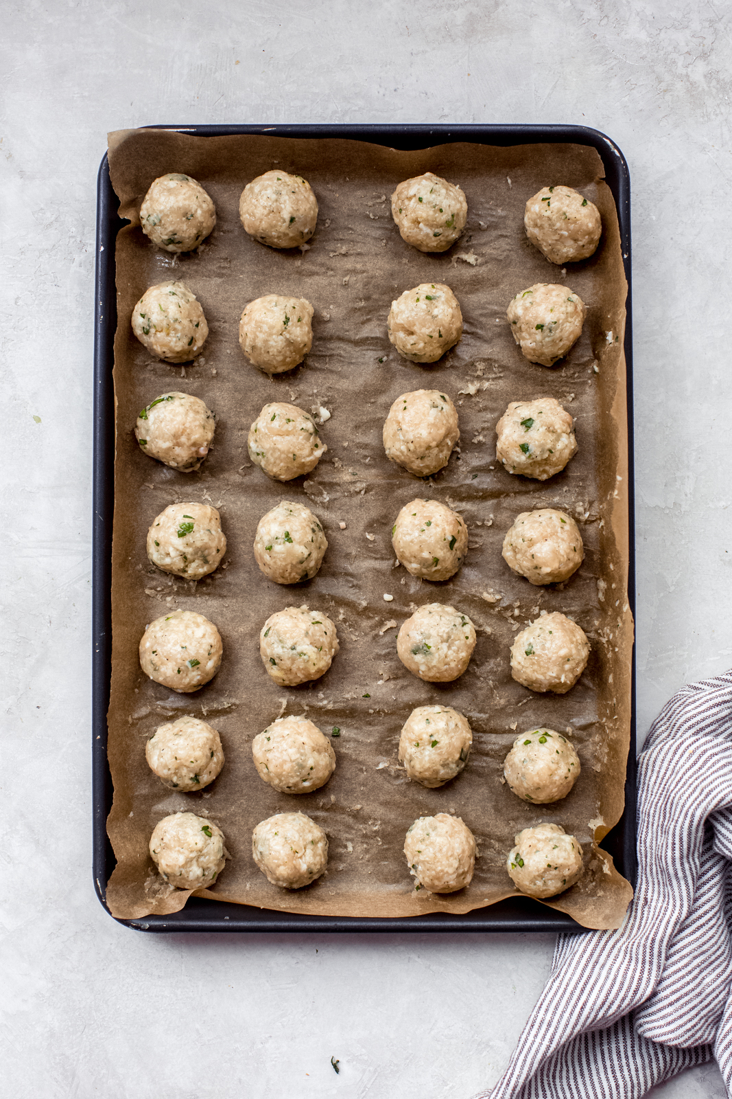 uncooked chicken meatballs on a baking sheet