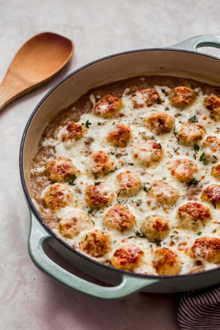 prepared chicken meatballs topped with melted cheese in cast iron pot