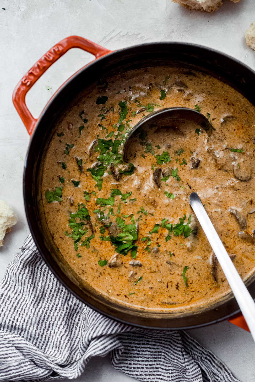 mushroom soup topped with parsley in a cast iron pot with ladle