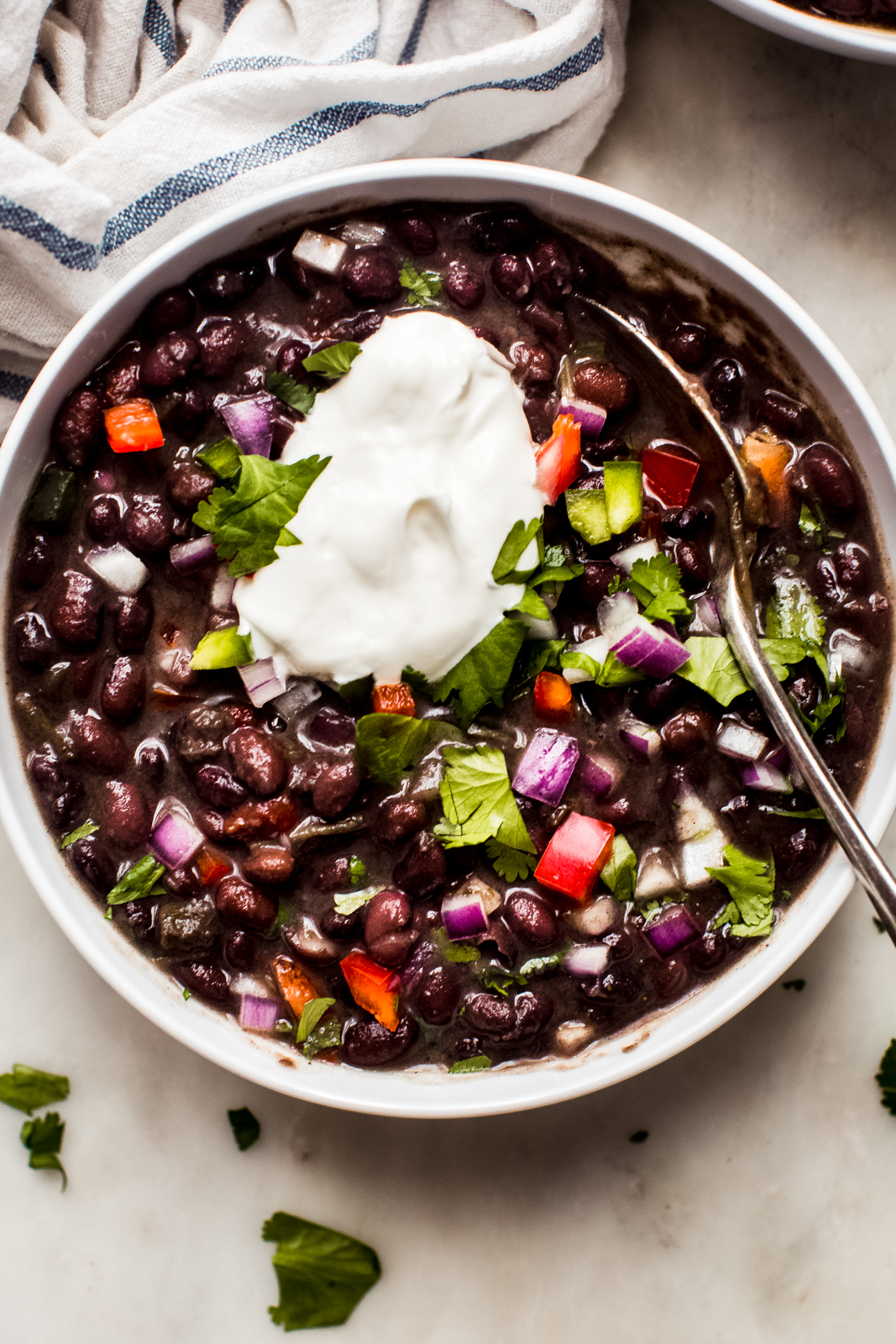 bowl of black bean soup topped with sour cream on marble