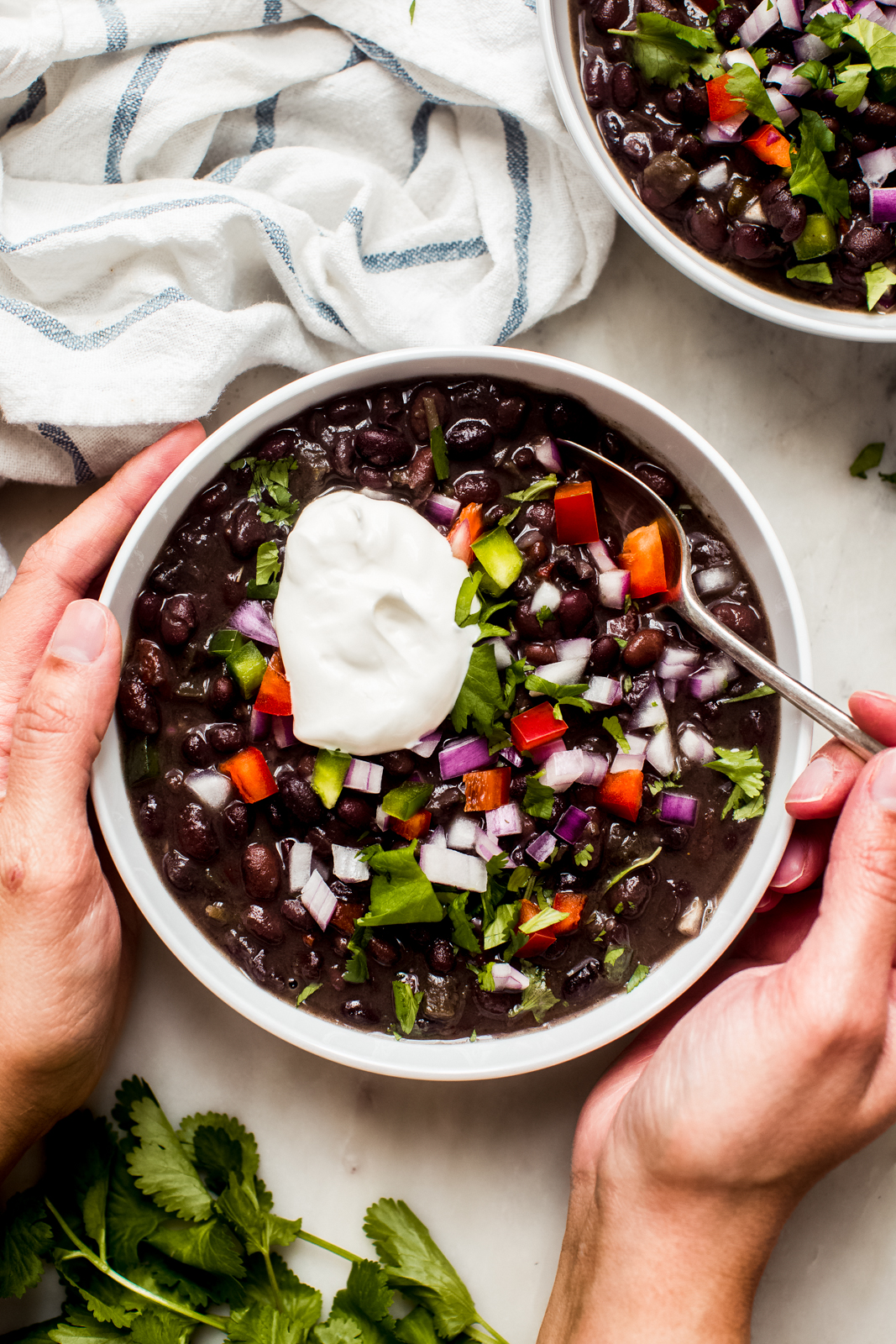hands around a black bean soup bowl holding spoon