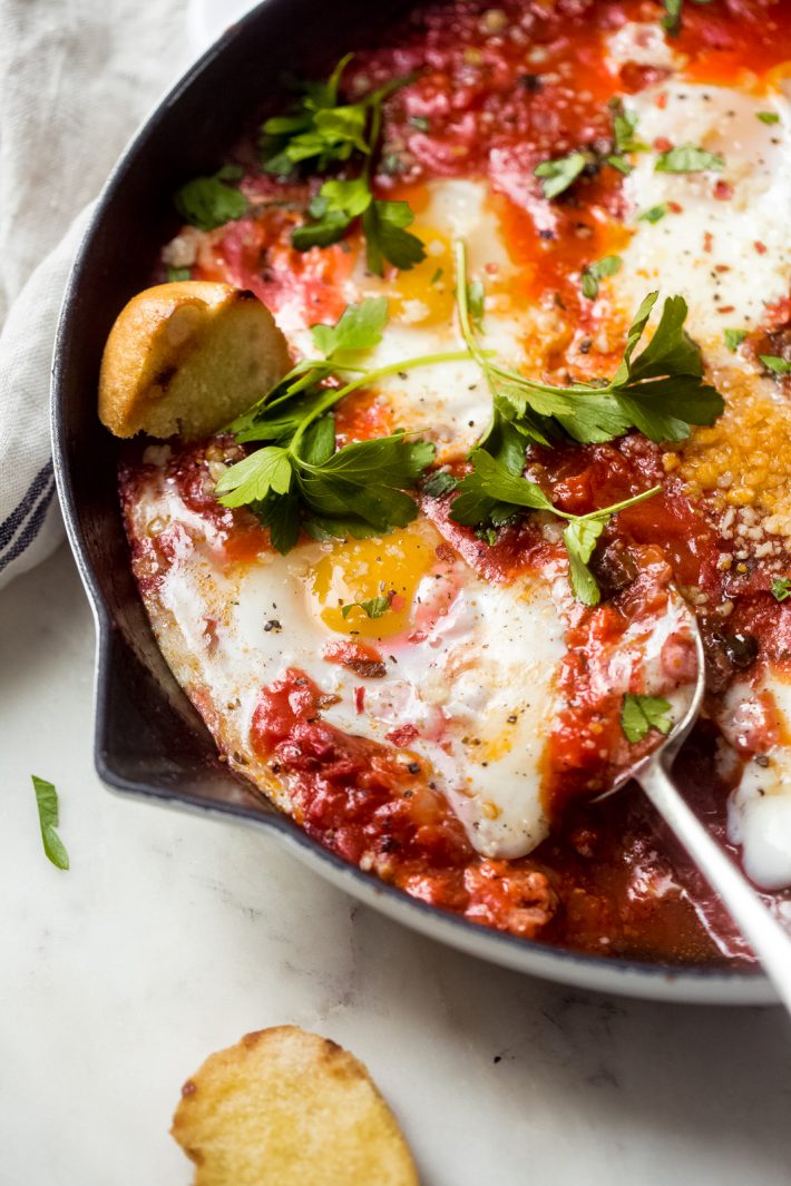 close up of eggs poached in tomato sauce