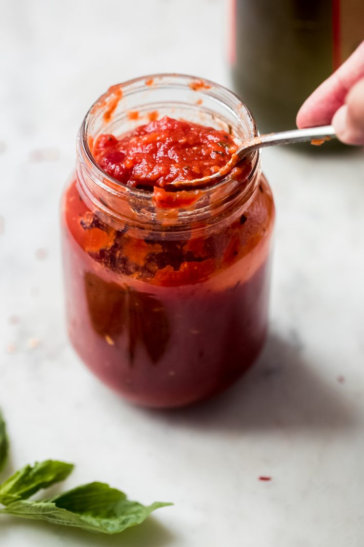 close up of pizza sauce in a jar with a spoon