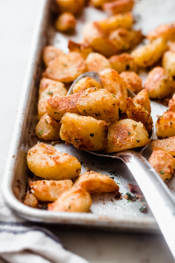 crispy roasted potatoes on a metal spoon resting on sheet pan