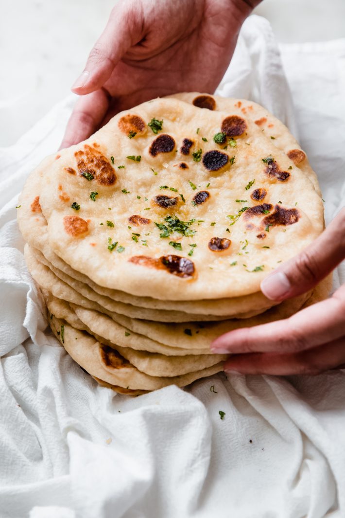 holding a stack on freshly made garlic naan
