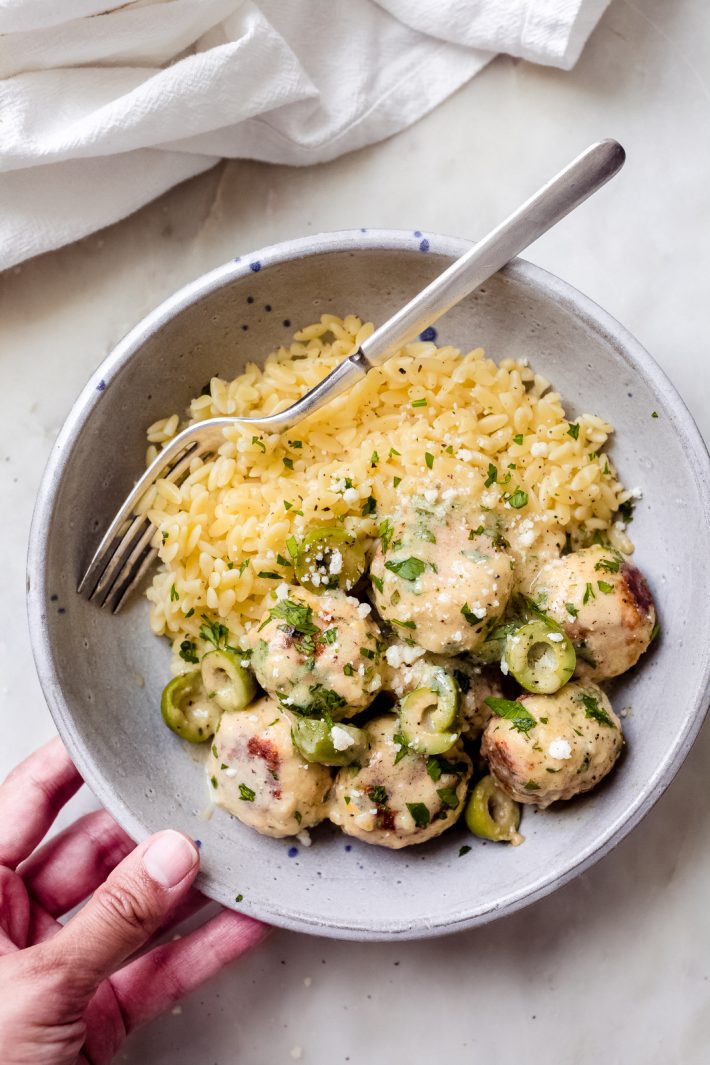 chicken meatballs in lemon sauce with cooked orzo in speckled bowl