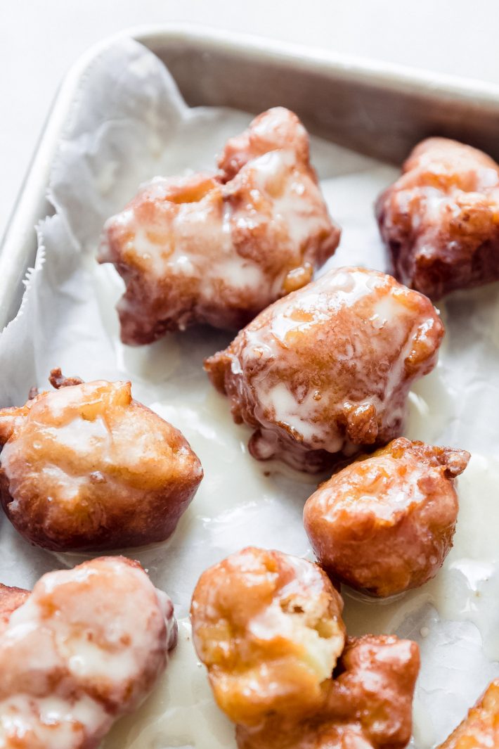 maple-glazed apple fritters on baking sheet lined with wax paper