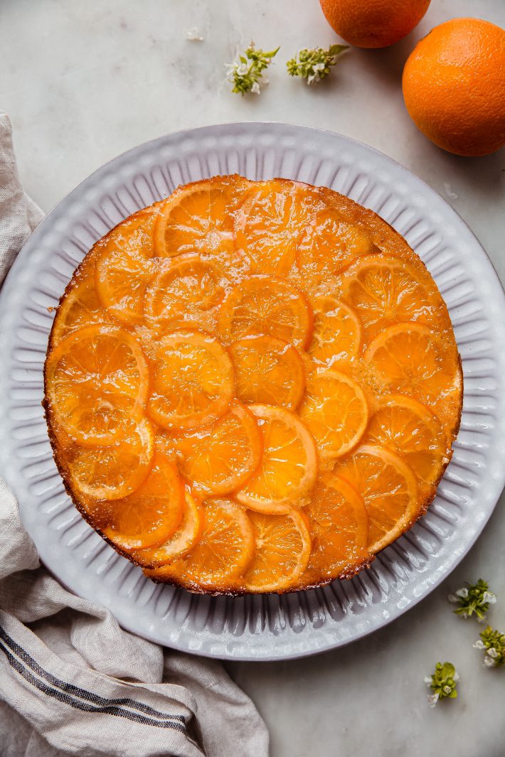 Italian orange cake topped with candied oranges on white plate