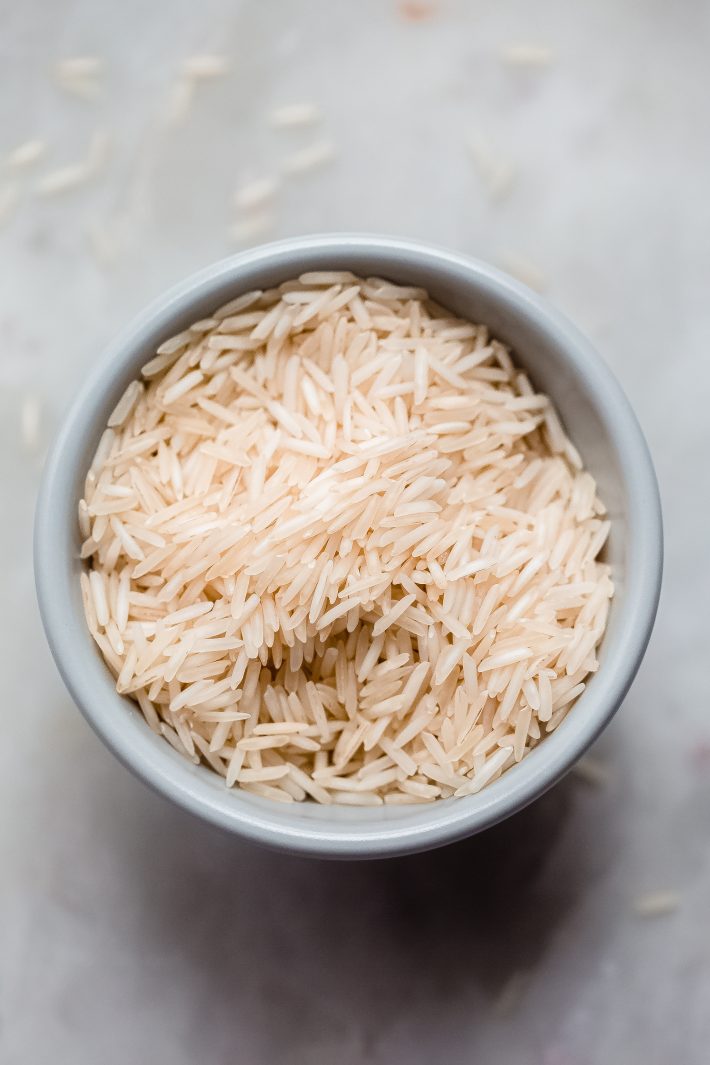 dried basmati rice in grey bowl on white marble