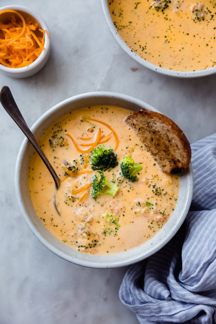 bowl of soup with spoon and bread on white marble 