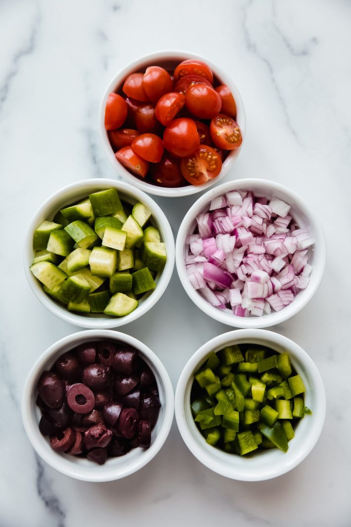 bowls holding individual ingredients for greek salad