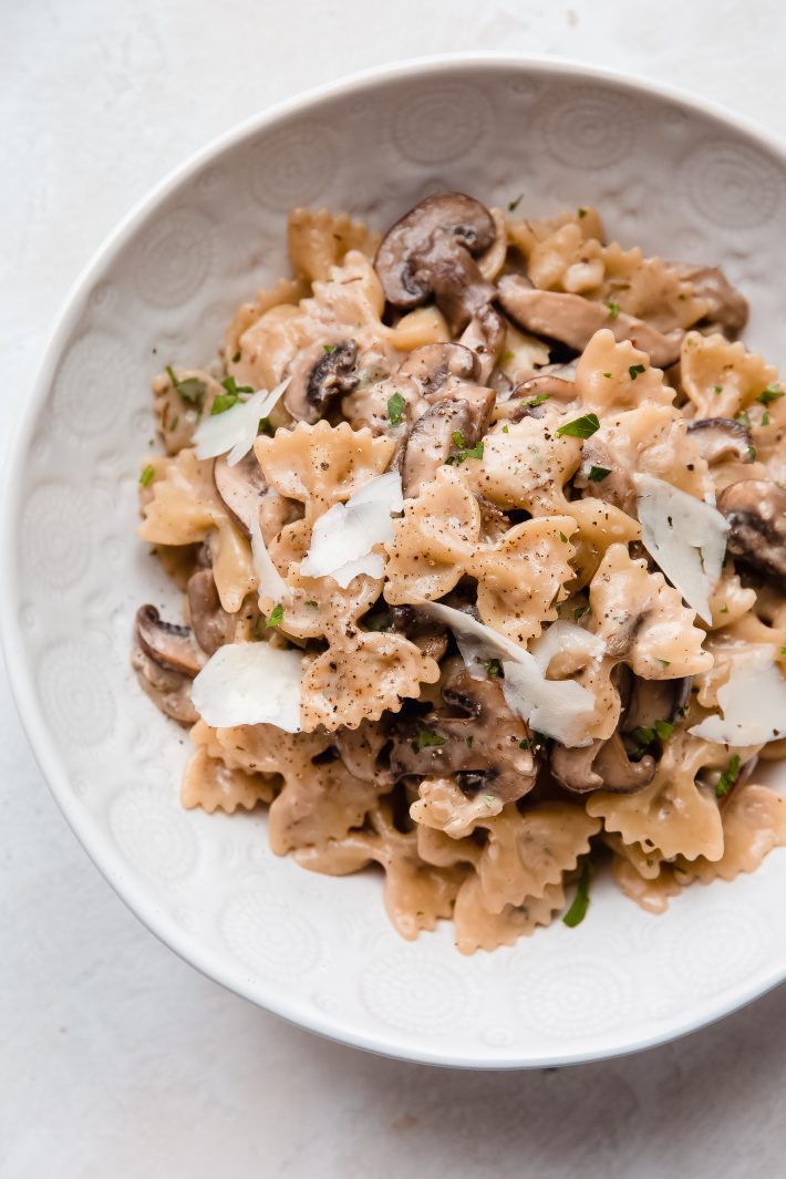 pasta with mushrooms in bowl with shaved parmesan, black pepper, and parsley