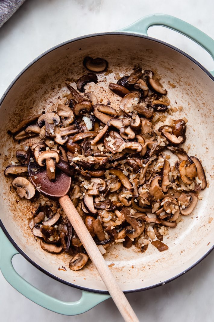 sautéed mushrooms, onions, garlic in cast iron pan on white marble