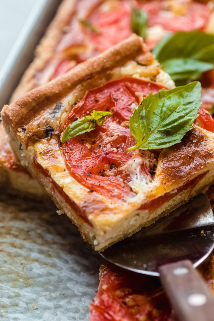 spatula with quiche showing cooked tomato and fresh basil