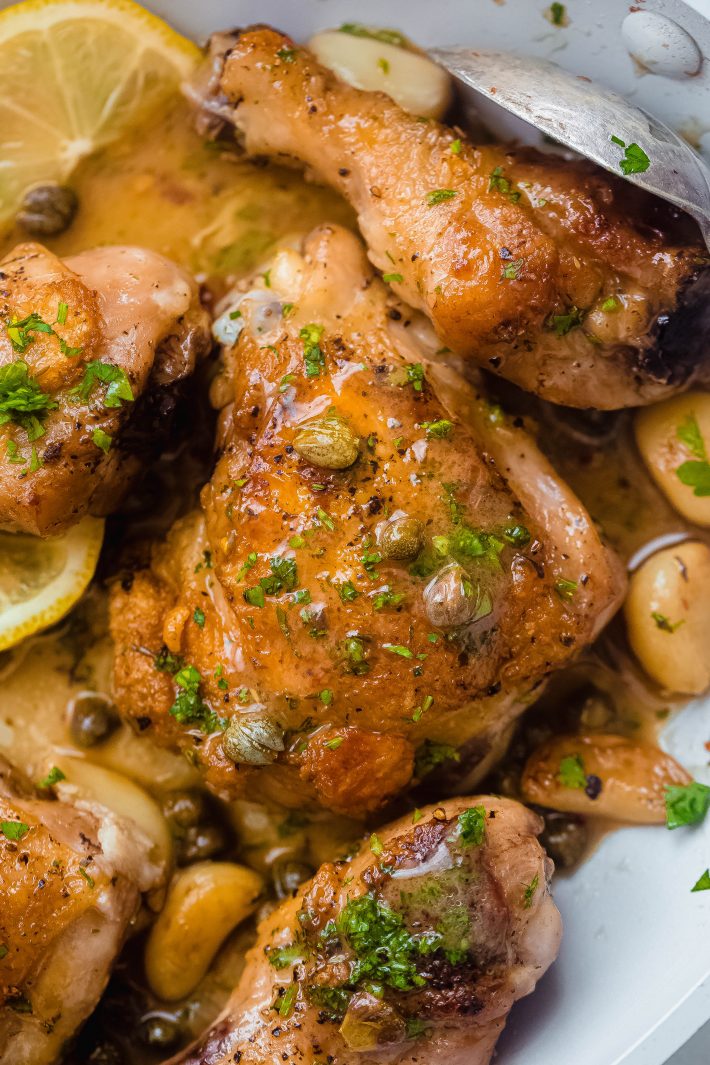 close up of braised chicken thighs with caper sauce on top