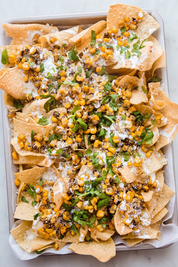 prepared elotes nachos on sheet pan with parchment paper