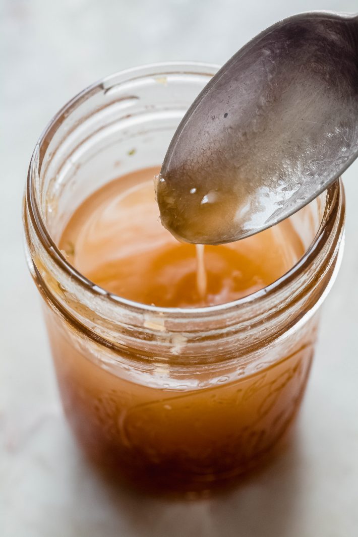 ginger dressing dripping from spoon into mason jar