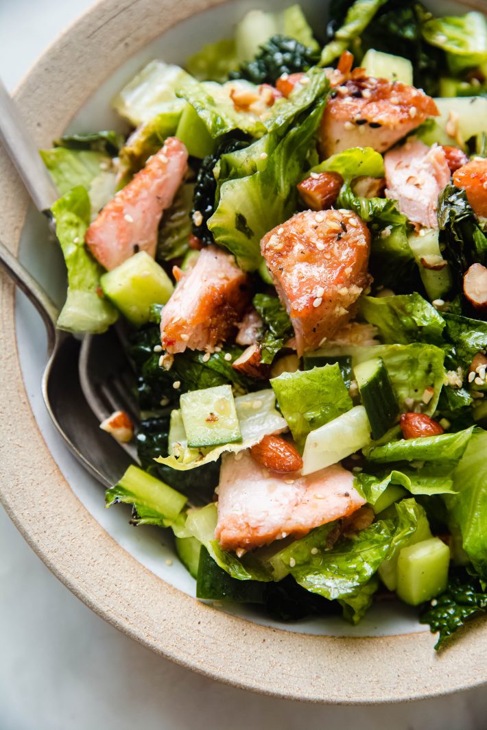 texture of romaine lettuce, cucumbers and flaked salmon in rimmed bowl