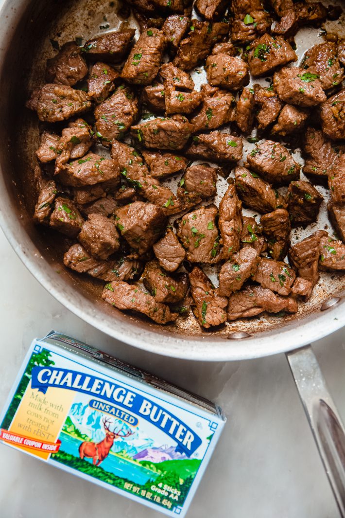 steak bites in skillet with challenge butter box on white marble