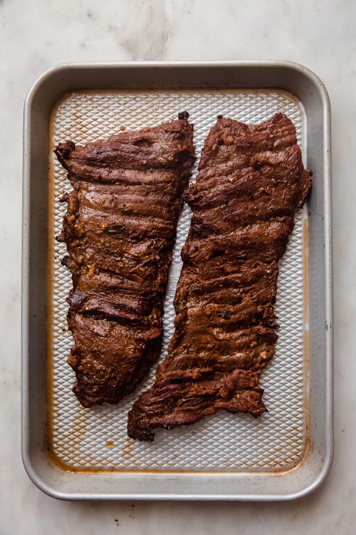 grilled steak resting on sheet pan