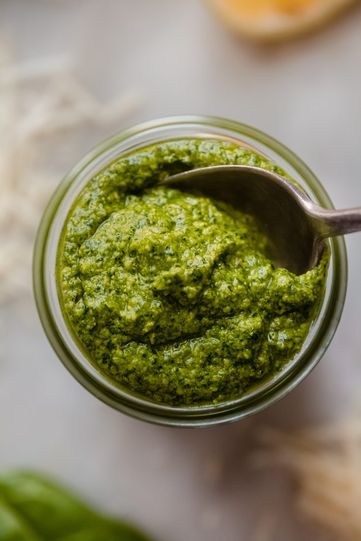 pesto being lifted with spoon from glass jar