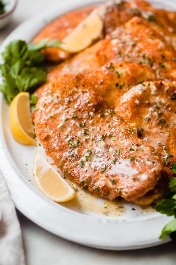 platter with parmesan chicken cutlets drizzled in lemon butter sauce