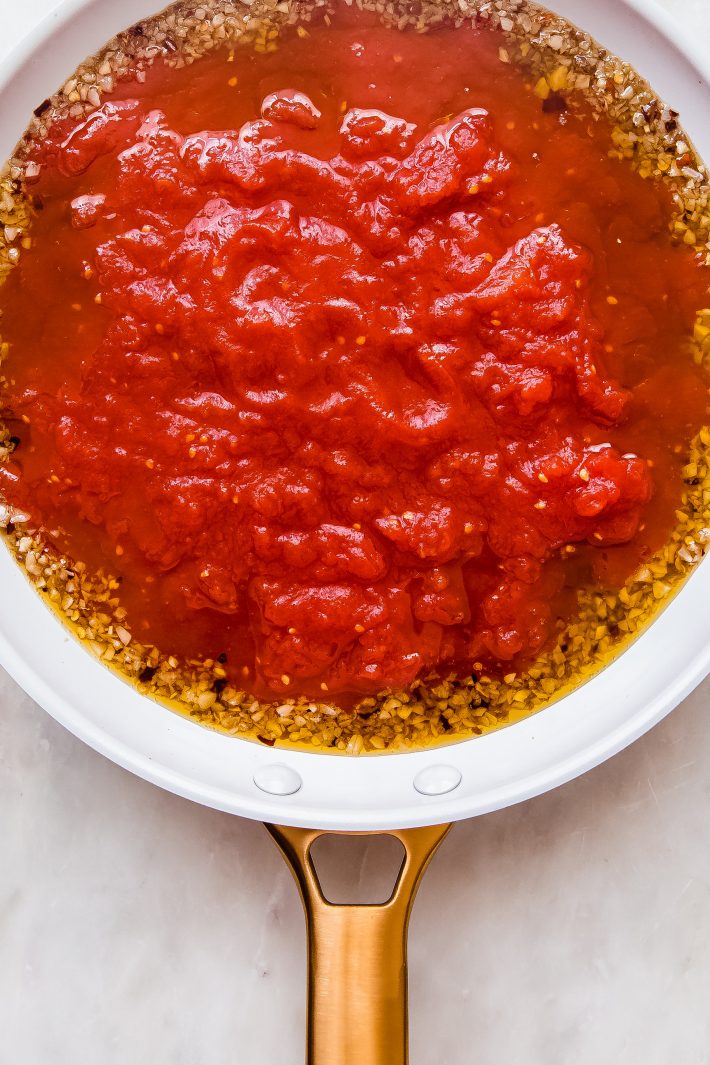 tomato sauce added to infused oil in skillet