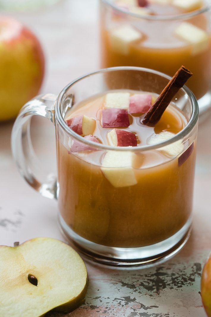 homemade apple cider with fresh apples and cinnamon stick in mug