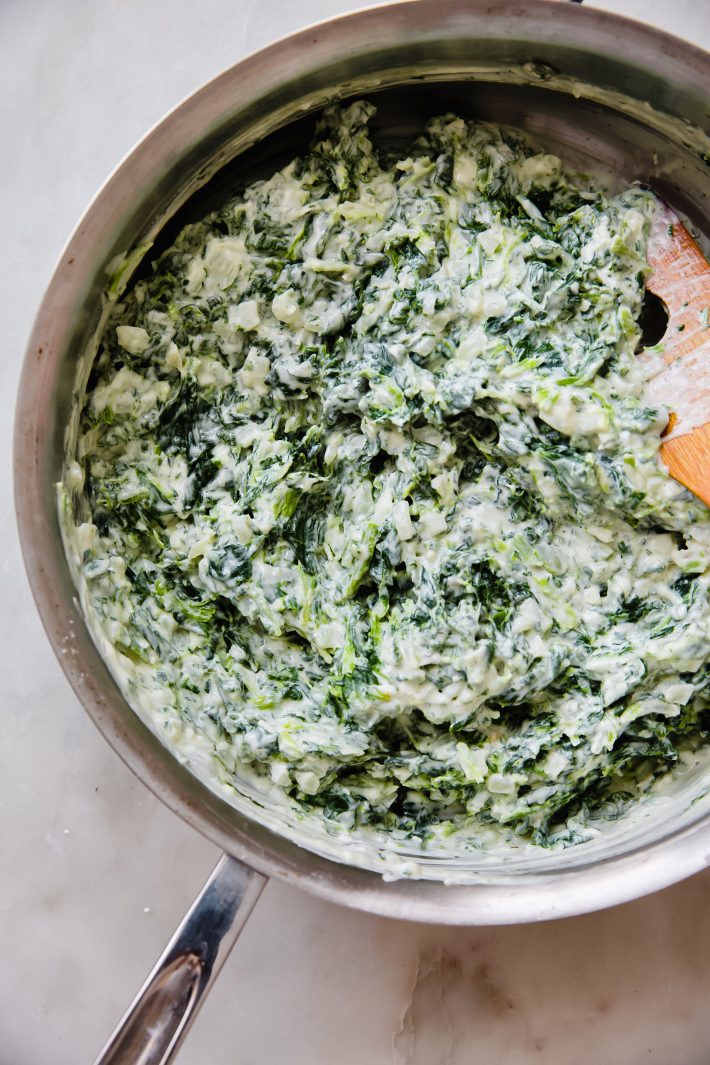creamed spinach in saute pan with wooden spoon