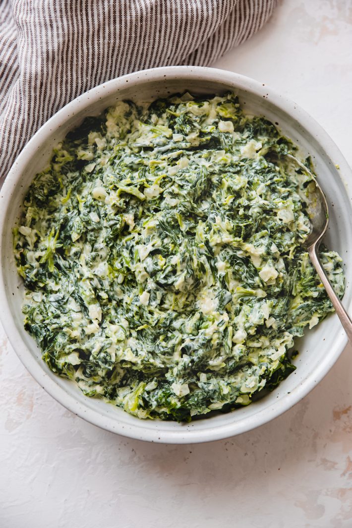 creamed spinach in speckled bowl with spoon