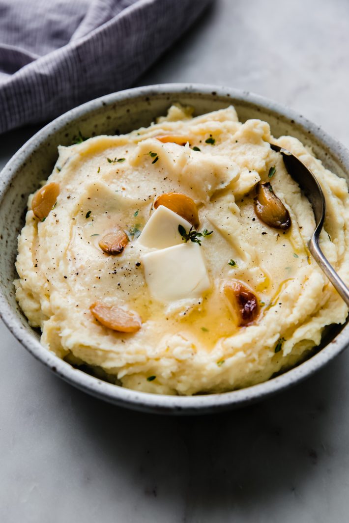 garlic mashed potatoes in speckled bowl with spoon