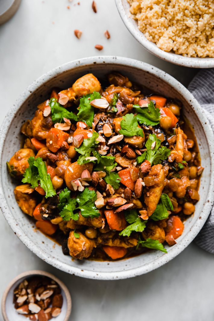 tagine in bowl topped with chopped almonds and cilantro