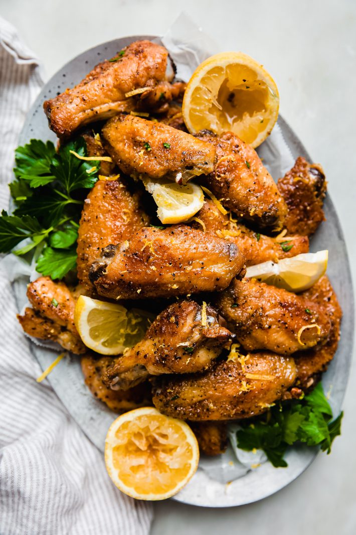 lemon pepper wings on tray with lemons and parsley