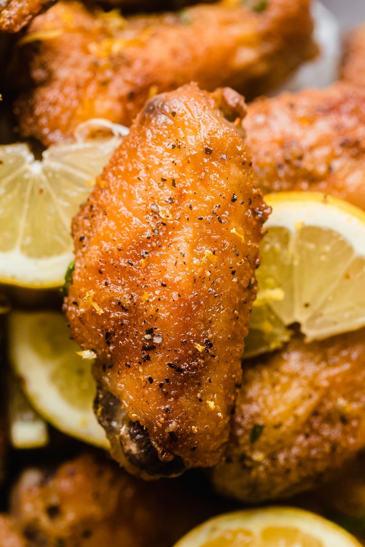 chicken wing with lemon zest and pepper surrounded by lemon slices