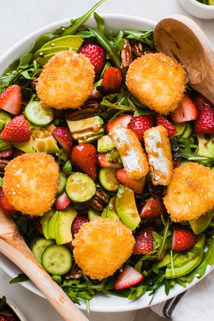 bowl of fried goat cheese on strawberry salad with wooden spoons