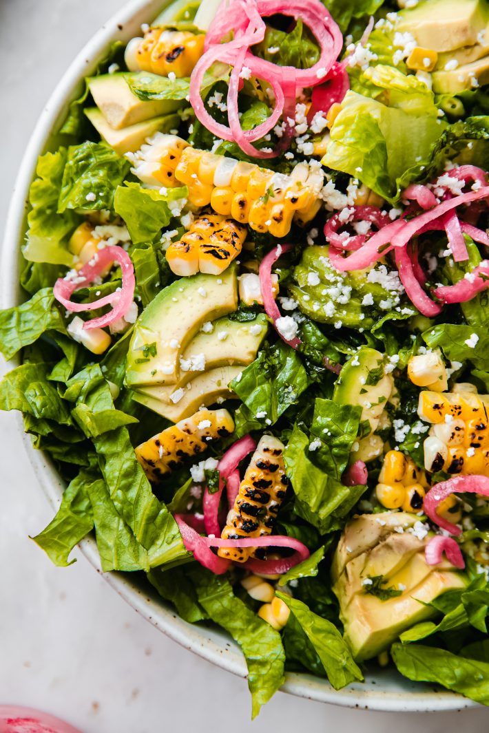 corn avocado salad topped with pickled onions romaine and cotija cheese