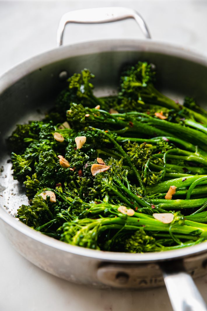 tender broccolini in pan with garlic chips and red pepper flakes