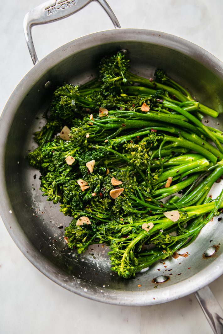 cooked broccolini in pan with garlic chips