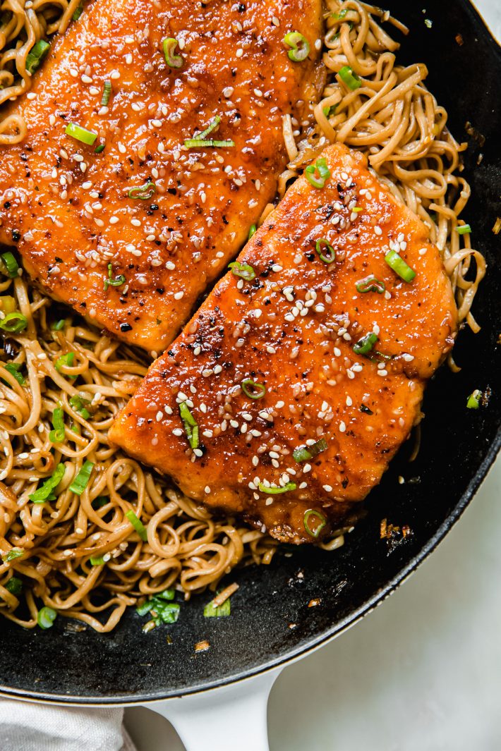 salmon fillets topped with scallions and sesame seeds on noodles