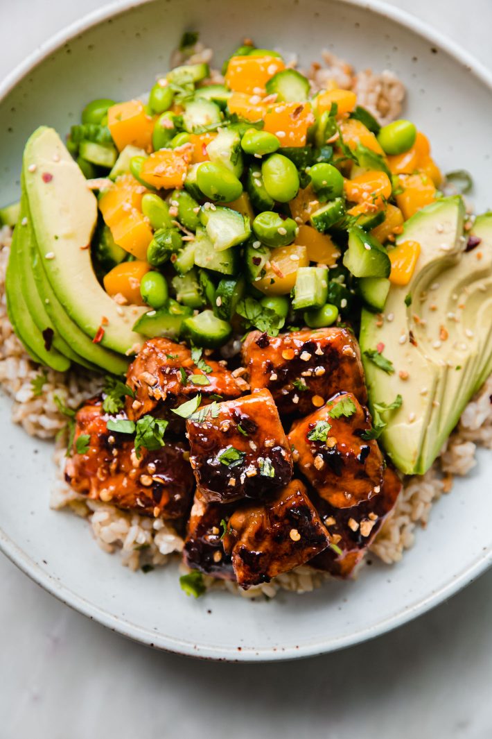 Rice bowls topped with salmon pieces, avocados and more