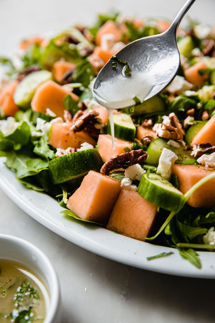 drizzling dressing over melon salad