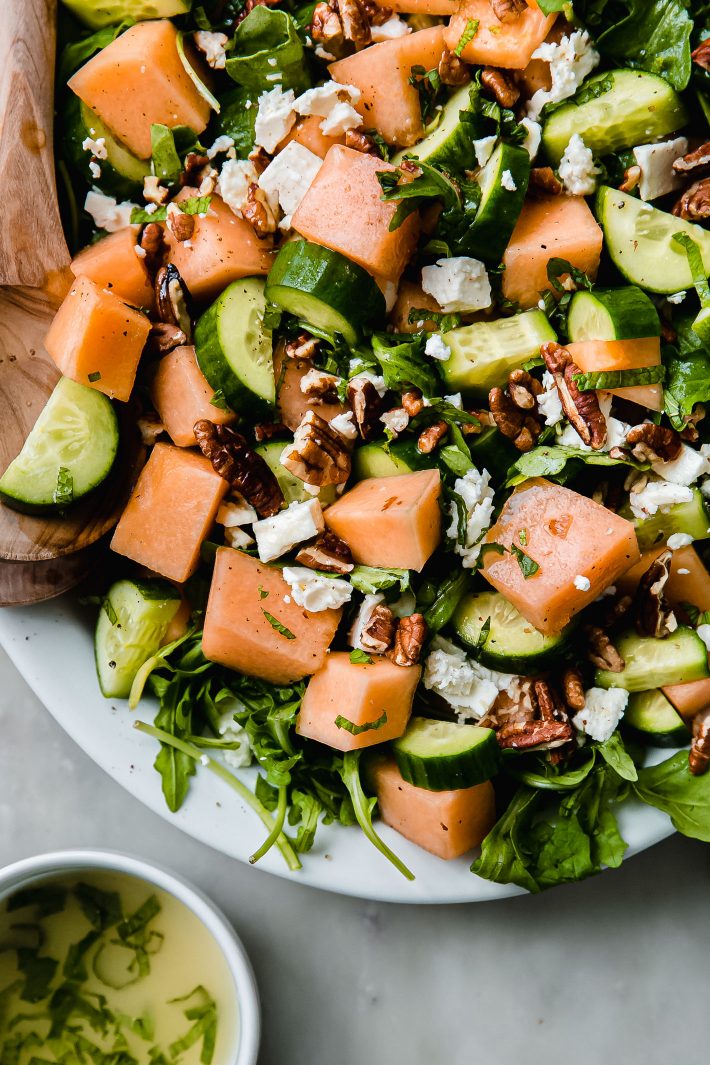 cucumber cantaloupe salad topped with mint pecans and feta on platter