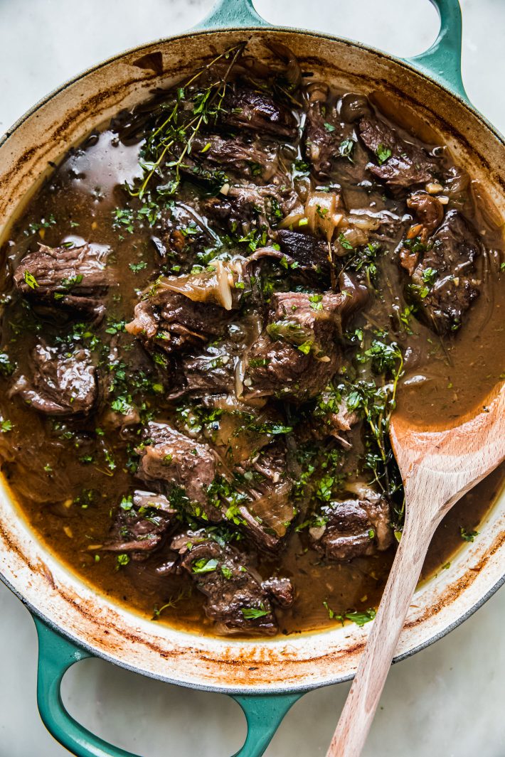braised beef in dutch oven with wooden spoon