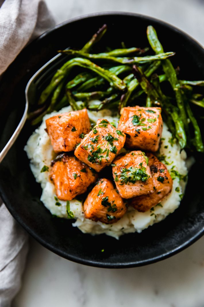 salmon chunks with garlic butter over mashed potatoes with green beans