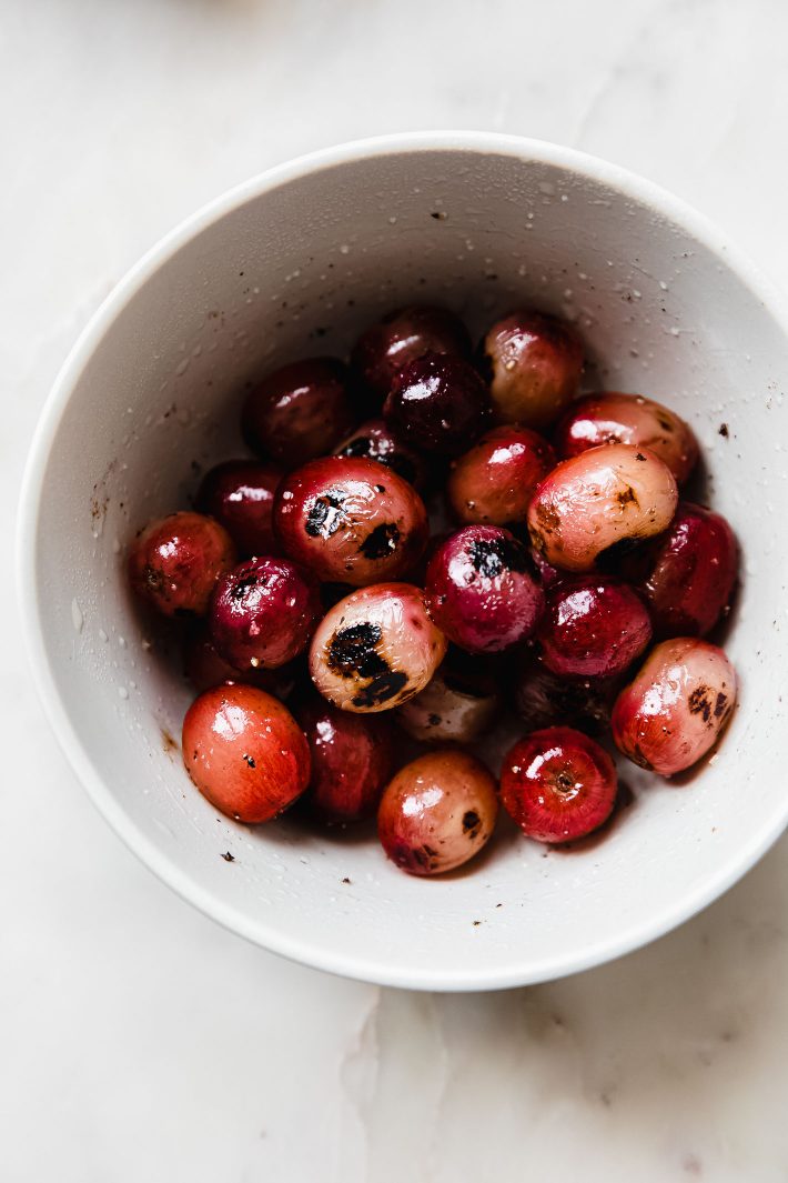 charred grapes with kosher salt and pepper in bowl